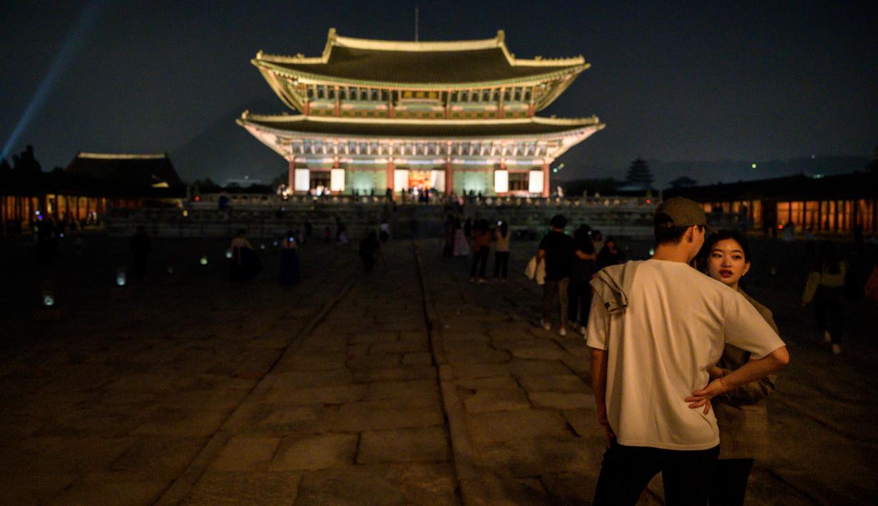 Gambar pada 4 Oktober 2019, wisatawan berdiri di halaman Istana Gyeongbokgung saat kunjungan malam di pusat Seoul, Korea Selatan. Kunjungan malam tersedia pada minggu ketiga dan keempat setiap bulan mulai dari 26 April sampai 31 Oktober, kecuali pada bulan Agustus. (Photo by Ed JONES / AFP)