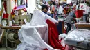 Pekerja menjahit bendera merah putih di kiosnya, kawasan Pasar Senen, Jakarta, Rabu (5/8/2020). Menjelang peringatan HUT ke-75 Kemerdekaan RI, sejumlah pedagang mengaku penjualan pernak-pernik bendera merah putih menurun 50 persen dibanding tahun lalu akibat COVID-19. (Liputan6.com/Faizal Fanani)