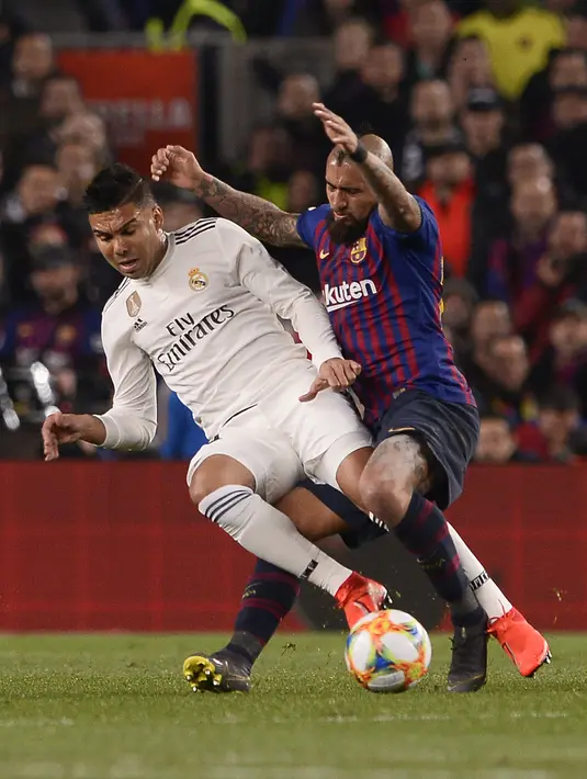 Gelandang Barcelona, Arturo Vidal berebut bola dengan gelandang Real Madrid, Casemiro pada pertandingan leg pertama semifinal Copa del Rey (Piala Raja) di stadion Camp Nou di Barcelona pada 6 Februari, 2019. (AFP/Josep Lago)