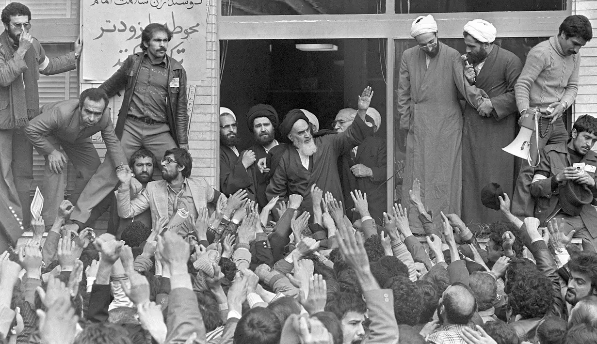 Pemimpin spiritual Iran, Ayatollah Khomeini (tengah) melambaikan tangan kepada pengikutnya ketika dia muncul di balkon markas besarnya di Teheran, Iran, 1 Februari 1979. Ayatullah Khomeini memimpin Revolusi Islam Iran. (AP Photo/Campion, File)