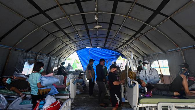 Pasien menerima perawatan di tempat penampungan sementara di luar Rumah Sakit Regional Sulbar, Mamuju, Minggu (17/1/2021). Mereka dirawat di dalam tenda darurat untuk mengantisipasi gempa susulan pascagempa 6,2 yang mengguncang Majene dan Mamuju, Sulawesi Barat pada Jumat (15/1). (ADEK BERRY/AFP)