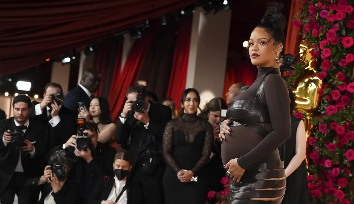 Pose penyanyi Rihanna untuk fotografer setibanya di karpet sampanye, pengganti karpet merah, Academy Awards ke-95 atau Oscar 2023 di Teater Dolby di Hollywood, California pada Minggu, 12 Maret 2023, waktu setempat. Penyanyi sekaligus pengusaha ini menambahkan pulasan lipstik merah cerah dan manikur yang serasi. (Photo by Jordan Strauss/Invision/AP)