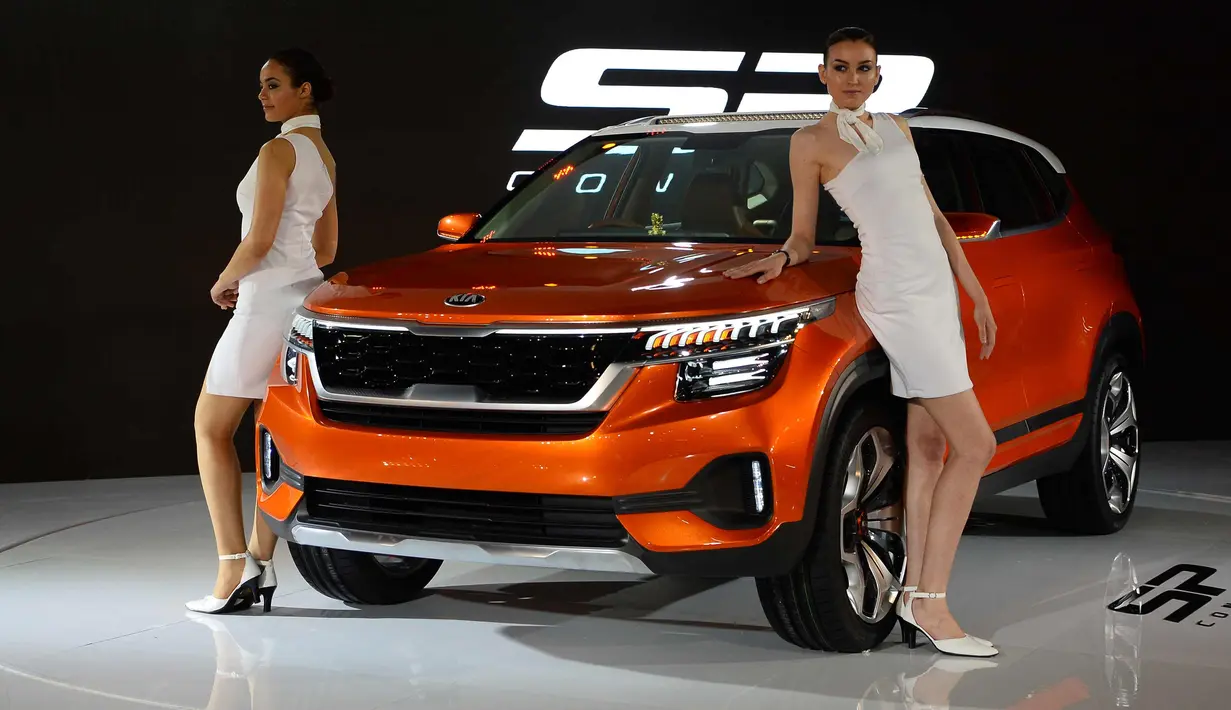 Dua model berpose di sebelah mobil konsep KIA SP yang baru diluncurkan saat Indian Auto Expo 2018 di Greater Noida, New Delhi, India, (7/2). (AFP Photo/Sajjad Hussain)