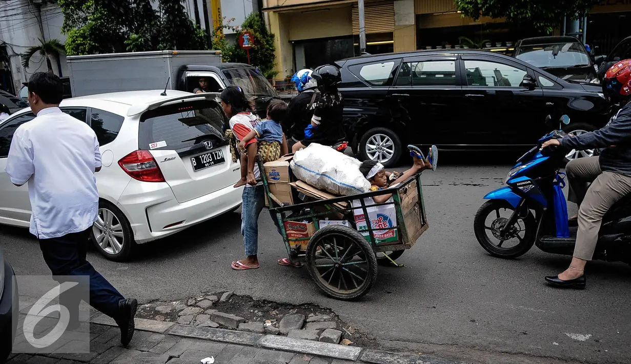 Ditengah kemacetan Jakarta seorang ibu membawa dua orang anaknya bersama dengan gerobak yang berisi barang bekas, mengitari jalan mengumpulkan barang bekas yang di bisa dijual, Jakarta, Kamis (6/10). (Liputan6.com/Faizal Fanani)
