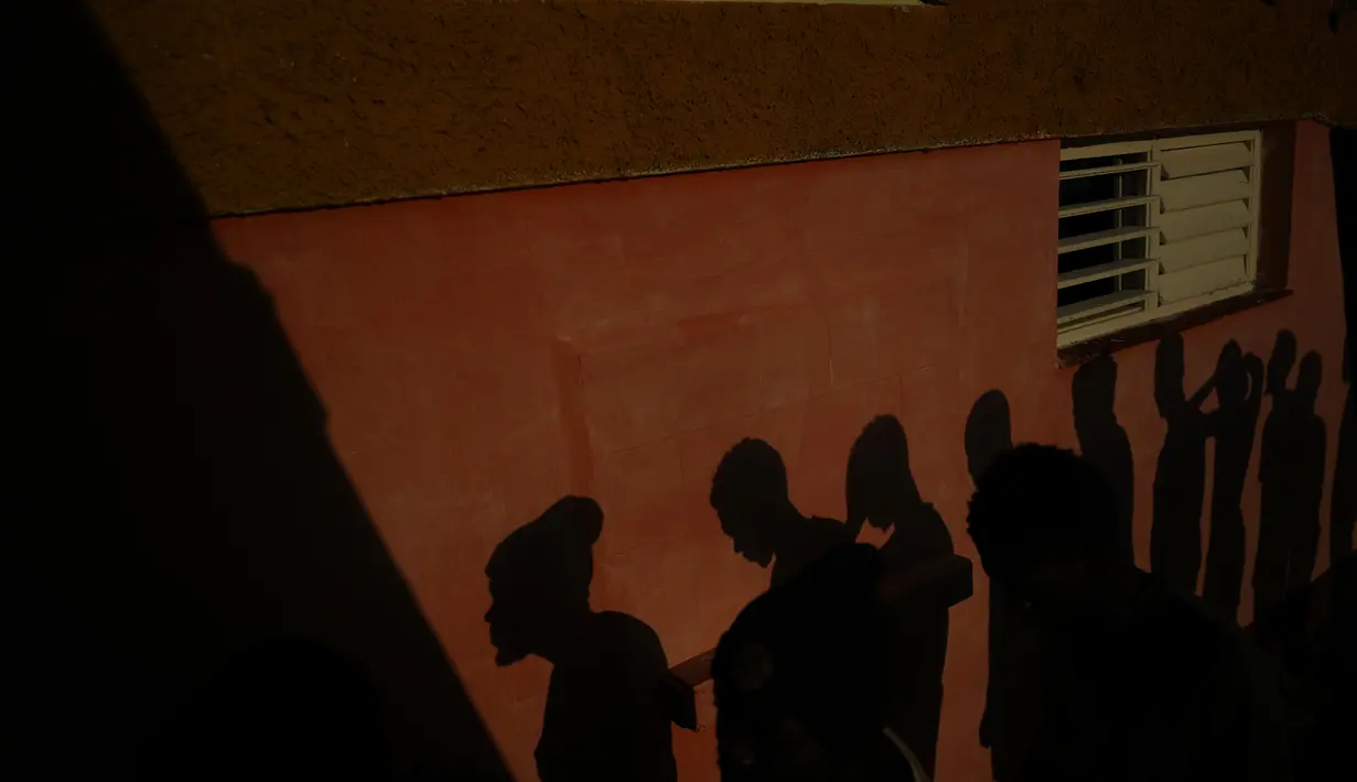 Bayangan para migran Haiti dipajang di dinding saat mereka menunggu untuk menerima makanan di sebuah perkemahan wisata di Sierra Morena, di provinsi Villa Clara, Kuba Kuba (25/5/2022). (AP Photo/Ramon Espinosa)