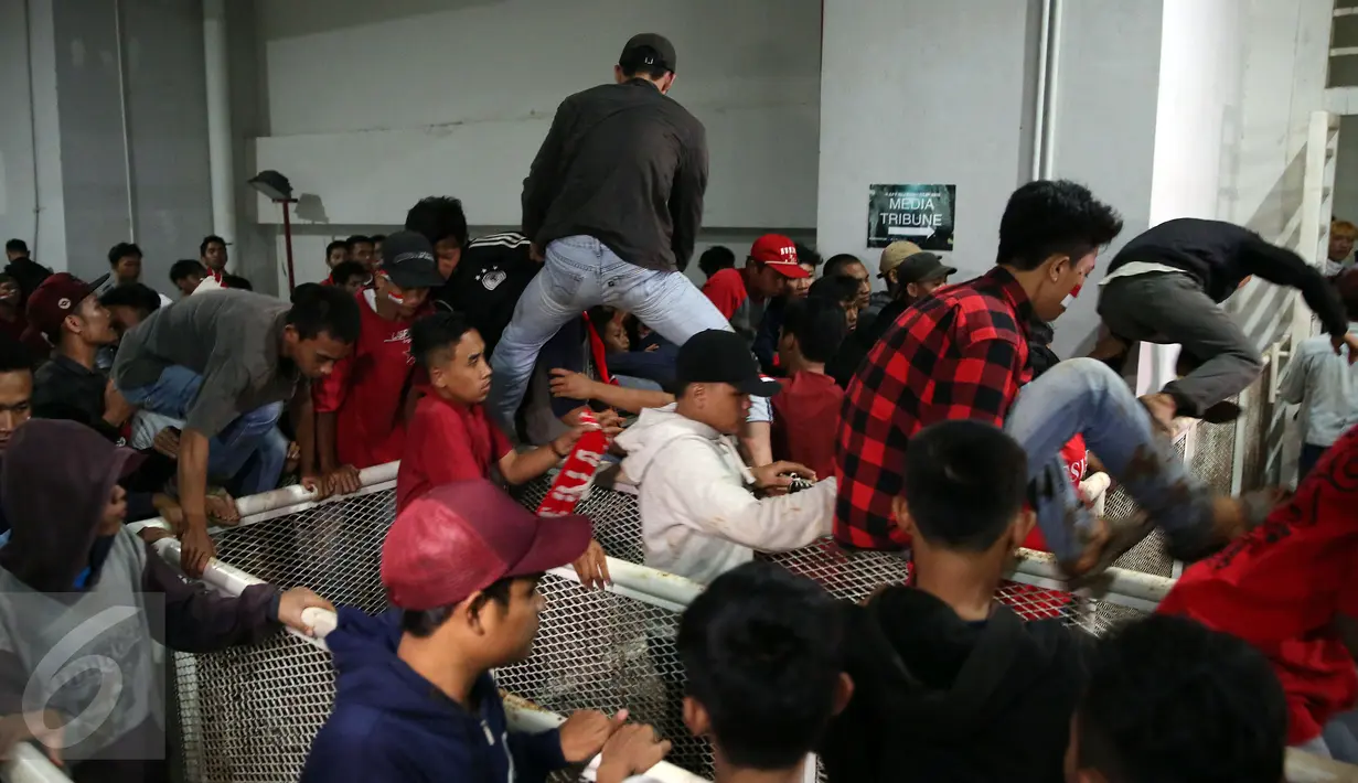Pendukung Timnas Indonesia nekat memanjat pagar pembatas untuk berusaha masuk ke dalam tribun saat berlangsungnya leg pertama final Piala AFF 2016 antara Indonesia melawan Thailand di Stadion Pakansari, Bogor, Rabu (14/12). (Liputan6.com/Johan Tallo)