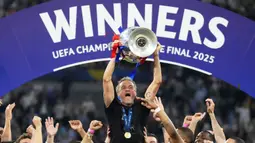 Pelatih PSG, Luis Enrique, mengangkat trofi Liga champions 2024/2025 di Stadion Allianz Arena, Minggu (01/06/2025) dini hari WIB. (AP Photo/Matthias Schrader)