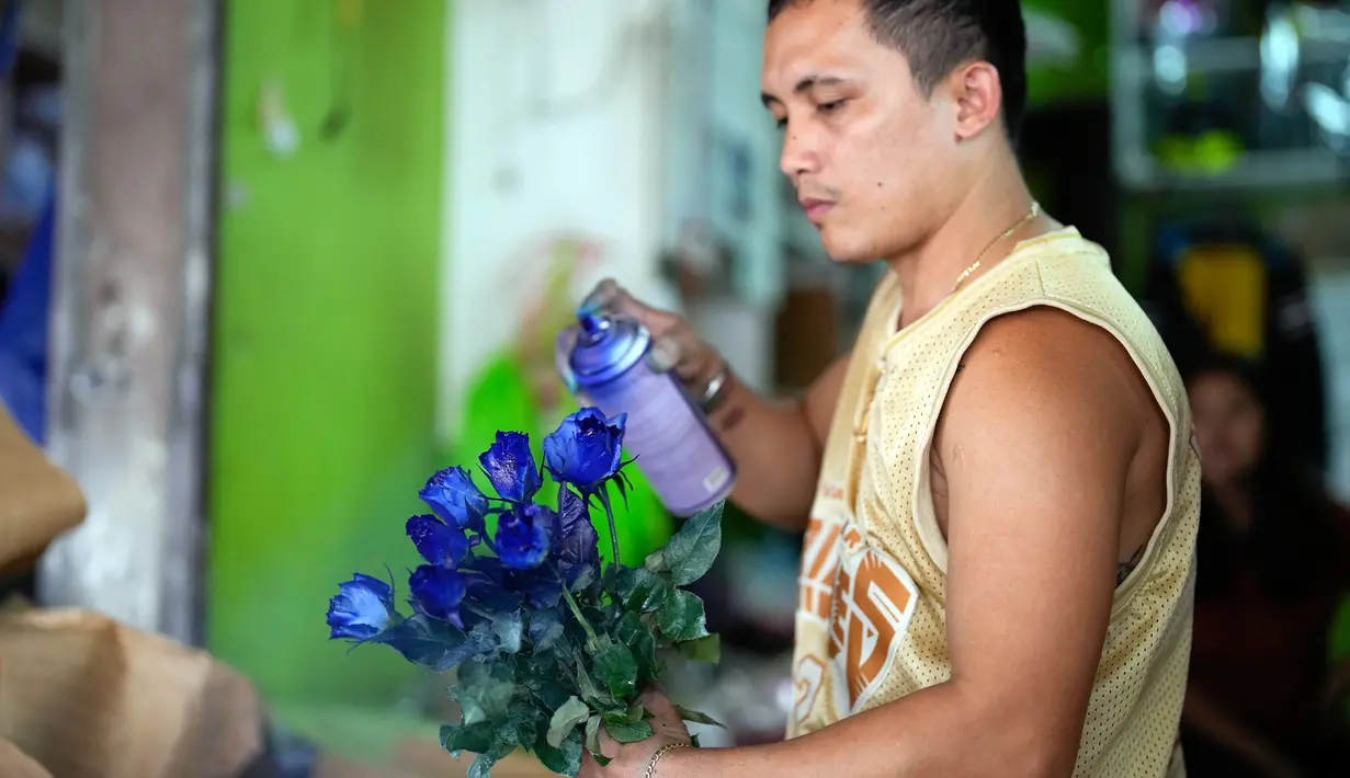 Seorang pekerja menyemprot bunga mawar agar terlihat lebih menarik di pasar bunga di Manila, Filipina, Senin (13/2/2023). Buket tersebut merupakan bagian dari gimmick Hari Kasih Sayang oleh seorang pemilik toko bunga. (AP Photo/Aaron Favila)