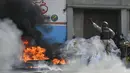 polisi mendorong ban yang terbakar ke sisi jalan agar mobil bisa lewat sat orang-orang memprotes meningkatnya kekerasan di lingkungan Lalue, Port-au-Prince, Haiti, Rabu (14/7/2021). Presiden Haiti Jovenel Moise dibunuh pada 7 Juli. (AP Photo/Matias Delacroix)