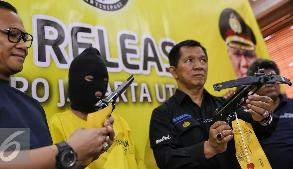 Petugas menujukan senjata api dan panah tembak saat rilis di Polres Jakarta Utara, Senin (25/1). Dalam penggrebekan petugas berhasil menyita 20,74 Gram Sabu, sejumlah senjata api berikut amunisi dan sebuah granat nanas aktif. (Liputan6.com/Faizal Fanani)
