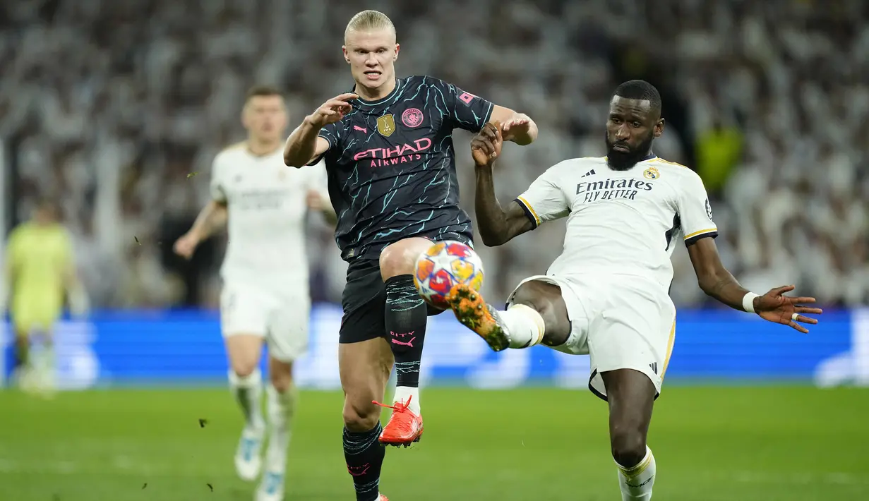 Striker Manchester City, Erling Haaland (kiri) berebut bola dengan bek Real Madrid, Antonio Rudiger pada laga leg pertama babak perempatfinal Liga Champions 2023/2024 di Santiago Bernabeu Stadium, Selasa (9/4/2024) malam. (AP Photo/Manu Fernandez)