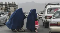 Wanita mengenakan burqa menyeberang jalan saat mereka berjalan menuju taksi di Kabul, Afghanistan, 31 Juli 2021. (SAJAD HUSSAIN/AFP)