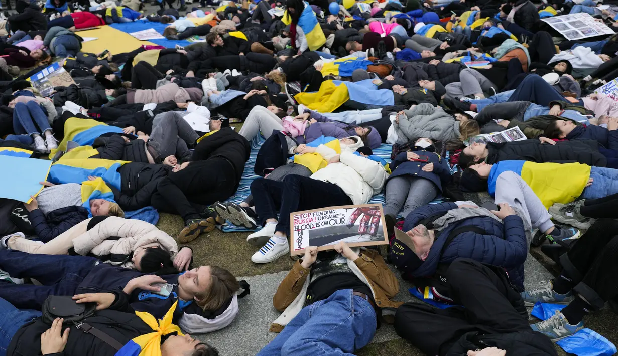 Orang-orang berbaring di tanah melambangkan mereka yang tewas dalam perang di Ukraina selama demonstrasi menentang invasi Rusia, di depan gedung Reichstag di Berlin, Jerman, 6 April 2022. Pengunjuk rasa menuntut Berlin berhenti membeli minyak dan gas Rusia. (AP Photo/Markus Schreiber)