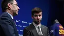 Bek Barcelona, Gerard Pique menyimak Presiden Barcelona FC, Josep Maria pada konferensi pers pengumuman resmi perpanjangan kontraknya di stadion Camp Nou, Senin (29/1). Bek timnas Spanyol itu meneken kontrak baru hingga 30 Juni 2022. (LLUIS GENE/AFP)