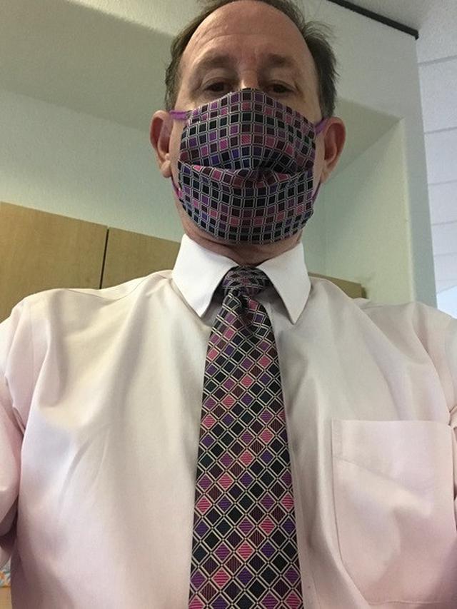 Pria kenakan motif masker dan dasi yang sama