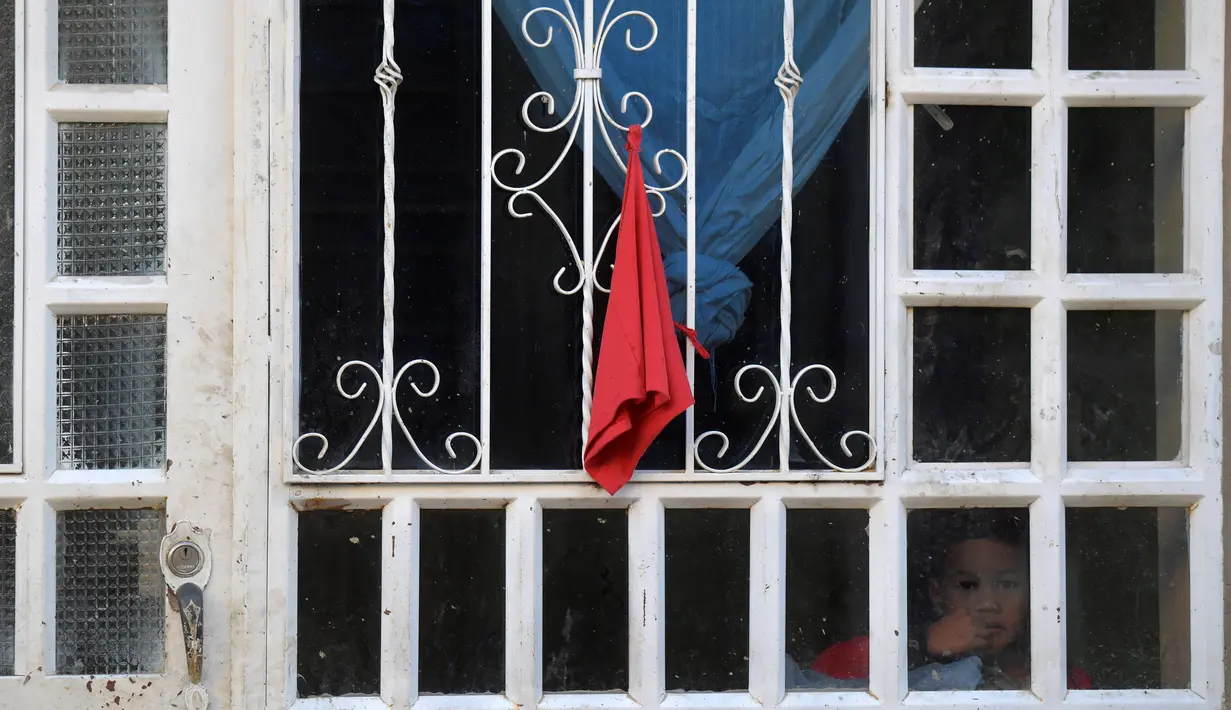 Orang-orang menggantungkan kain merah di rumah mereka untuk meminta bantuan makanan selama lockdown di kotamadya Soacha, dekat Bogota, 4 April 2020. Presiden Kolombia Ivan Duque menetapkan lockdown dari 24 Maret hingga 13 April sebagai langkah mencegah penyebaran virus corona. (Raul ARBOLEDA/AFP)