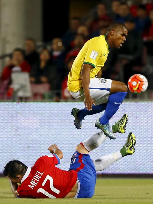 Gelandang Brasil, Douglas Costa berusaha melewati gelandang Chile, Gary Medel pada kualifikasi Piala Dunia 2018 di Santiago, Chile (8/10/2015). Chile menang atas Brasil dengan skor 2-0. (REUTERS/Ivan Alvarado)