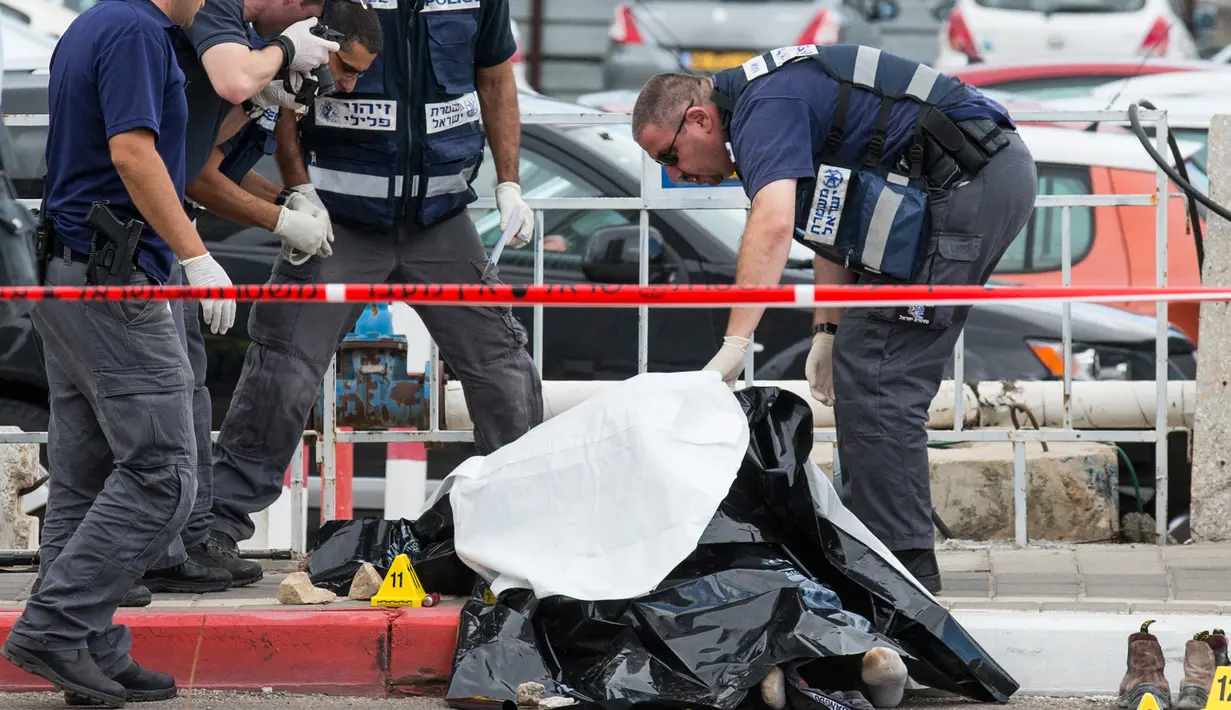 Polisi Israel memeriksa mayat pria Palestina yang ditembak mati usai menikam dua warga Israel di Tel Aviv, Kamis (8/10). Menurut juru bicara polisi Israel, pria Palestina itu menikam tentara wanita dengan obeng di Mulailah Street. (AFP PHOTO/JACK GUEZ)
