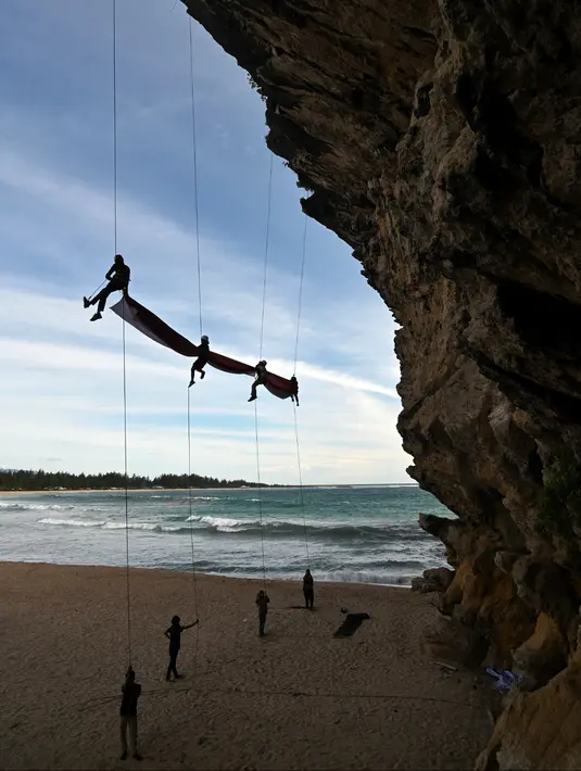 Sekelompok mahasiswa mengibarkan bendera Merah Putih berukuran besar menjelang perayaan Hari Ulang Tahun ke-77 Republik Indonesia di Pantai Lhoknga, Aceh, 16 Agustus 2022. Pengibaran bendera Merah Putih berukuran besar yang dilakukan pada sebuah tebing ini untuk memeriahkan Hari Ulang Tahun ke-77 Republik Indonesia. (CHAIDEER MAHYUDDIN/AFP)