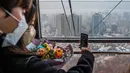 Sepasang kekasih berfoto selfie di dalam kereta gantung saat bangunan di latar belakang terlihat diselimuti kabut, selama kunjungan ke Menara Namsan pada hari yang tercemar di Seoul, Korea Selatan, Rabu (15/12/2021). (AFP/Anthony Wallace)