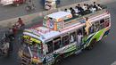 Sebuah bus dengan penumpang di atas atap berjalan di sepanjang jalan di Lahore pada 19 April 2023, saat orang-orang menuju kampung halaman mereka untuk merayakan Hari Raya Idul Fitri, yang menandai berakhirnya bulan puasa Ramadhan. (Photo by Arif Ali / AFP)