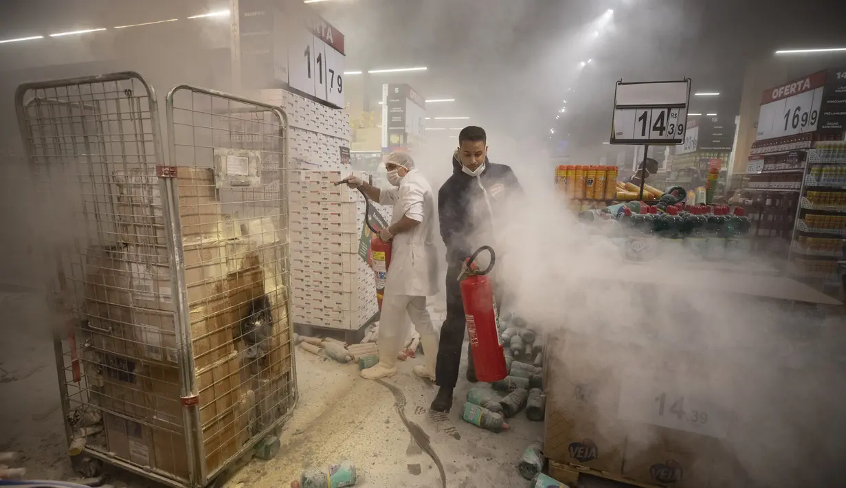 Karyawan memadamkan api yang dibuat oleh pengunjuk rasa di dalam supermarket Carrefour selama protes terhadap pembunuhan pria kulit hitam Joao Alberto Silveira Freitas di supermarket Carrefour, pada Hari Kesadaran Kulit Hitam Nasional Brasil di Sao Paulo, Brasil (20/11/2020). (AP Photo/Bruna Prado)