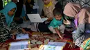 Seorang guru (kedua kiri) menggunakan bahasa isyarat membimbing siswa tunarungu di rumahnya di Pekan Bada, dekat Banda Aceh (14/9/2020). Para guru telah membimbing siswa yang kekurangan akses ke internet untuk kelas online di rumah mereka setelah wabah virus merebak. (AFP Photo/Chaideer Mahyuddin)