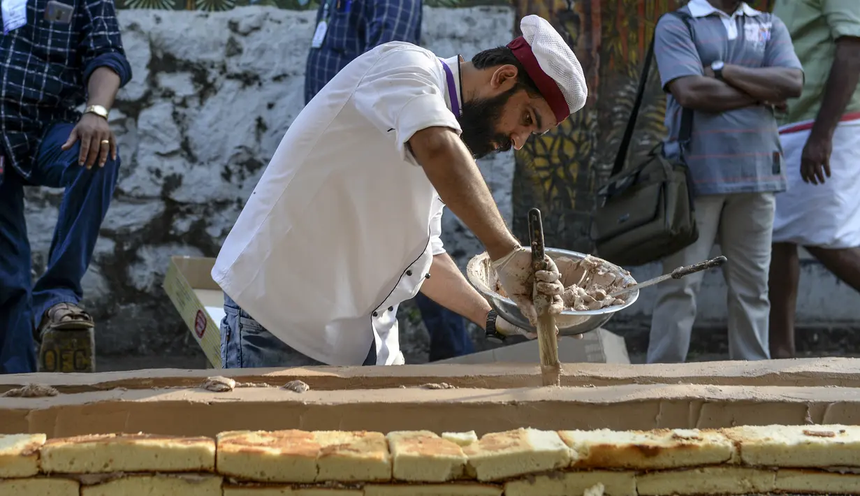 Seorang tukang roti menyelesaikan kue sepanjang 6,5 km untuk kue terpanjang dunia, di Thrissur di negara bagian Kerala, India selatan (15/1/2020). Ratusan pembuat roti dan koki di India selatan membuat kue terpanjang di dunia. (AFP/Arun Sankar)