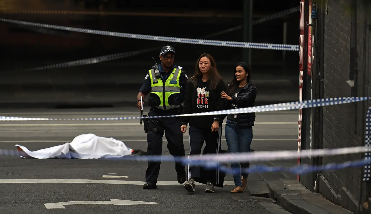 Polisi membawa warga menjauh dari TKP setelah insiden penikaman di Melbourne, Australia, Jumat (9/11). Pelaku menabrakkan mobil dan membakarnya sebelum menusuk tiga orang sekitar. (William WEST/AFP)