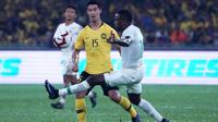 Gelandang Timnas Malaysia, Brendan Gan (kuning), berduel dengan striker Timnas Indonesia, Greg Nwokolo, di Stadion Nasional, Bukit Jalil (19/11/2019), dalam laga kelima Grup G kualifikasi Piala Dunia 2022 zona Asia. (AFP/STR)