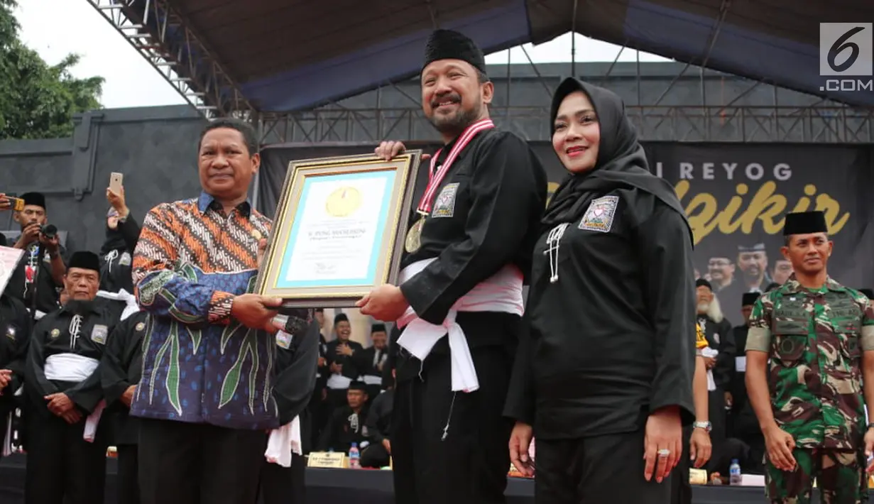 Bupati Ponorogo Ipong Muchlissoni (tengah) menerima Rekor MURI dari Leprid sebagai rekor zikir dan gerakan kolosal pencak silat dengan peserta pendekar terbanyak di Alun-alun Ponorogo, Jawa Timur, Minggu (30/12). (Liputan6.com/HO/Firdaus)