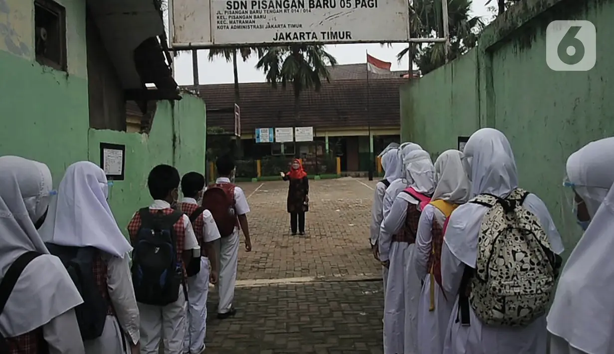 Murid berbaris memasuki gedung sekolah saat pembelajaran tatap muka (PTM) terbatas di SDN Pisangan Baru 05 Pagi, Jakarta, Senin (8/11/2021). Orangtua dan guru diwajibkan disiplin mengedukasi protokol kesehatan secara lisan maupun melalui media sosial. (merdeka com/Iqbal S. Nugroho)