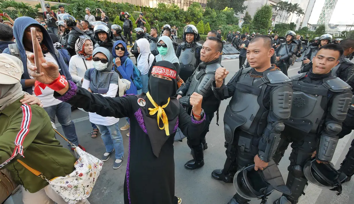 Seorang peserta aksi berswafoto dengan Polisi dari kesatuan Brimob saat gelar doa bersama di depan kantor Bawaslu, Jakarta, Jumat (24/5/2019). Mereka datang untuk mendoakan para demonstran yang meninggal saat aksi 21-22 Mei, pasca hasil penghitungan suara Pemilu 2019. (Liputan6.com/Herman Zakharia)