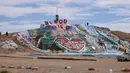 Turis mengunjungi Salvation Mountain, sebuah lereng bukti di Niland, California, Amerika Serikat. Dibangun dari kumpulan jerami, dempul jendela dan lebih dari 10,000 galon cat yang dipergunakan untuk membuat bukit tetap berdiri, dan melindunginya dari pasir dan angin gurun. (Robyn Beck/AFP)