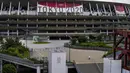 Seorang pekerja berjalan melalui pintu depan Stadion Nasional, satu bulan sebelum pembukaan Olimpiade Tokyo, di Tokyo, Rabu (23/6/2021). Olimpiade Tokyo dimulai pada 23 Juli dan penyelenggara mengizinkan penonton lokal menghadiri venue pertandingan dengan kapasitas 50 persen (AP Photo/Kiichiro Sato)