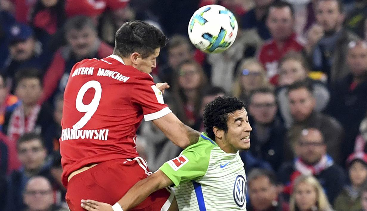 Striker Bayern Munchen, Robert Lewandowski, duel udara dengan pemain VfL Wolfsburg, William, pada laga Bundesliga, di Stadion Allianz, Kamis (22/9/2017). Bayern Munchen ditahan imbang 2-2 oleh VfL Wolfsburg. (AP/Matthias Balk)