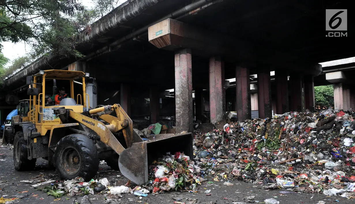 Petugas PPSU menggunakan alat berat mengangkut sampah di kolong Tol Wiyoto-Wiyono, Sungai Bambu, Jakarta, Selasa (15/1). Dalam sehari petugas kebersihan mengangkut sampah hingga 10 truk dengan berat total sekitar 100 ton. (Merdeka.com/Iqbal S. Nugroho)