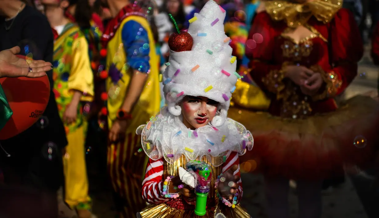 Seorang anak yang mengenakan pakaian badut ikut serta dalam parade badut tahunan di Sesimbra, Portugal pada Senin (4/3/2019). Tidak hanya orang dewasa anak-anak pun ikut merias diri menjadi badut. (PATRICIA DE MELO MOREIRA / AFP)