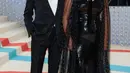 Mantan aktor Bond Pierce Brosnan tak perlu jadi siapa-siapa saat Met Gala. Dalam debutnya, ia mengajak sang istri Keely Shaye yang bersinar dengan gaun cape transparannya.  [Foto: @themetgalaofficial]