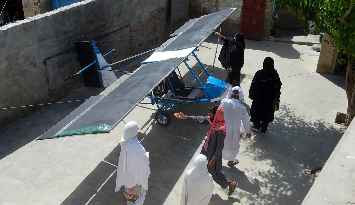 Warga melihat pesawat buatan Muhammad Fayyaz di Desa Tabur, Provinsi Punjab, Pakistan, 8 April 2019. Pesawat kecil tersebut dirakit menggunakan mesin dari alat pemotong aspal, sayapnya dari karung goni, dan roda-rodanya diambil dari roda becak. (ARIF ALI/AFP)