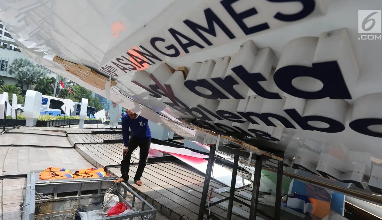 Pekerja memeriksa papan sosialisasi Asian Games 2018 yang roboh akibat hujan angin di Bundaran HI, Jakarta, Senin (11/9). Kontruksi besi penahan baliho patah Akibat hujan angin yang mengguyur Jakarta minggu (10/9) malam. (Liputan6.com/Faizal Fanani)