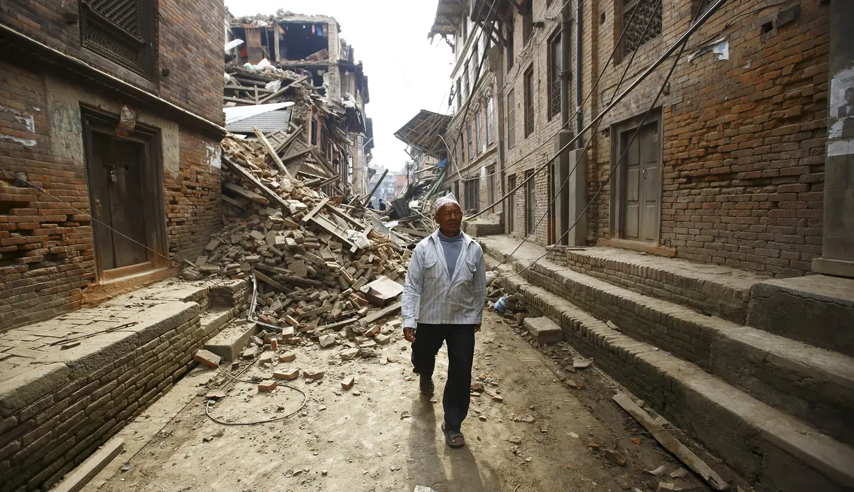 Seorang warga melintas di dekat reruntuhan bangunan akibat gempa berkekuatan 7,8 skala Richter, Nepal, Minggu (26/4/2015). Dikabarkan sekitar 500 orang lebih tewas dalam peristiwa tersebut (Reuters/Navesh Chitrakar)