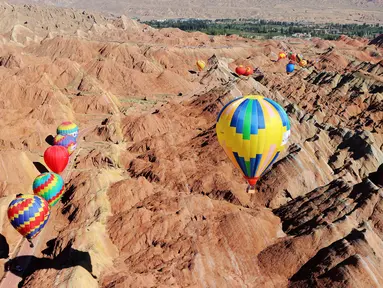 Sejumlah balon udara terbang di atas Taman Geologi Nasional Danxia di Zhangye, Provinsi Gansu, China barat laut, pada 26 Juli 2020. Sebuah festival balon udara internasional dibuka di Zhangye pada Minggu (26/7). Total 100 balon udara akan ditampilkan dalam festival tersebut. (Xinhua/Cheng Lin)