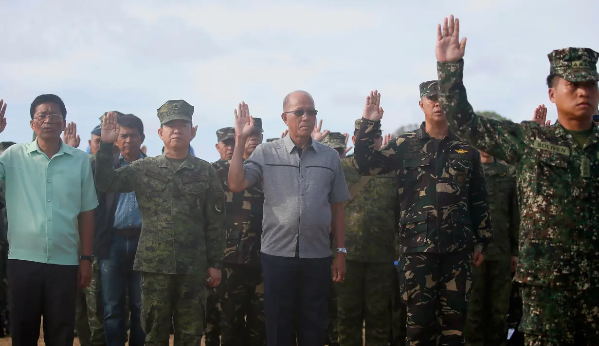 Menteri Pertahanan Delfin Lorenzana bersama Tentara Filipina saat mengikuti upacara pengibaran bendera di Pulau Thitu, Kepulauan Spratly, Laut China Selatan, Jumat (21/4). (AP Photo / Bullit Marquez)