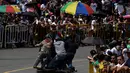 Penonton menyaksikan peserta menuruni bukit menggunakan kendaraan buatan sendiri selama festival kendaraan luncur dengan nama Car Festival ke 29 di Medellin, Kolombia pada 18 November 2018. (Photo by JOAQUIN SARMIENTO / AFP)