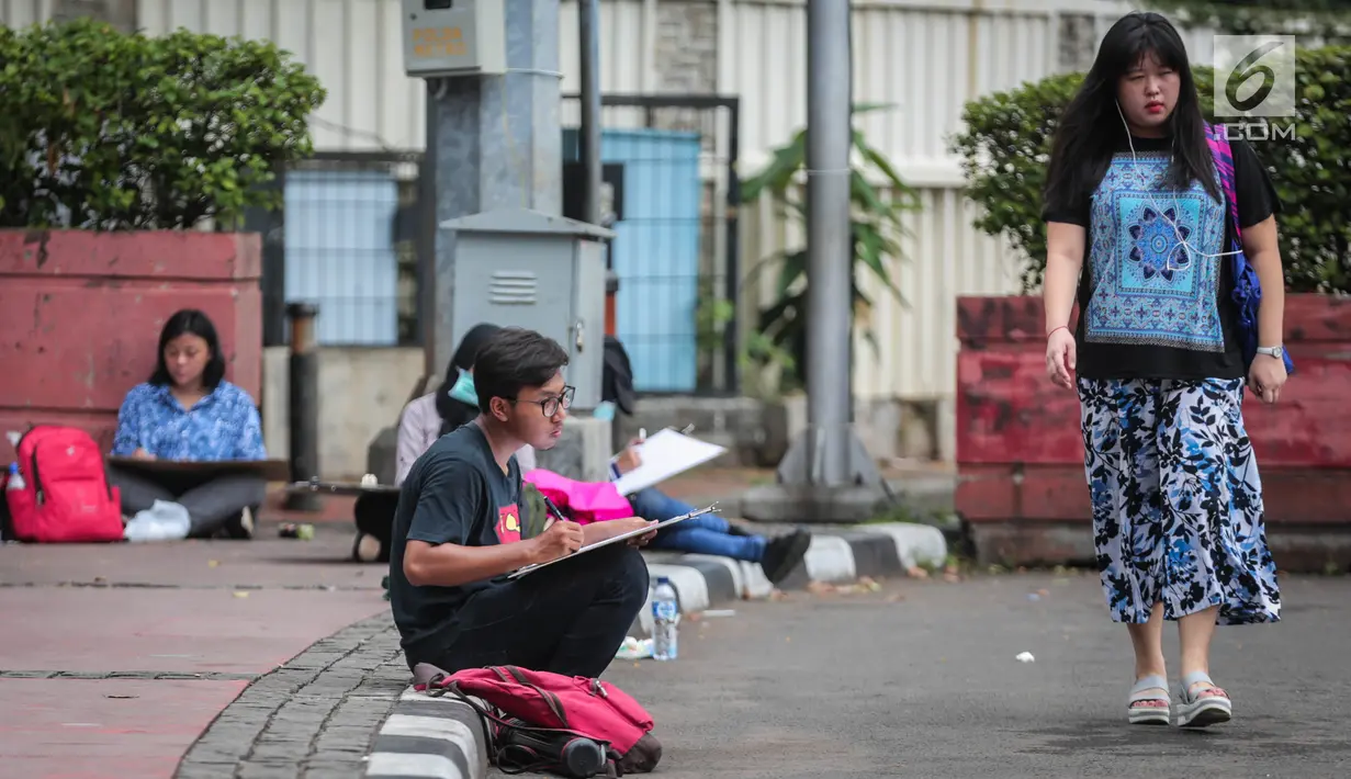 Sejumlah Mahasiswa IKJ Fakultas Seni Rupa duduk dipinggir jalan melukis suasana Bundaran HI, Jakarta Pusat, Kamis (19/10). Mereka melukis suasana Bundaran HI untuk mengaplikasikan ilmu yang didapatnya saat kuliah. (Liputan6.com/Faizal Fanani)