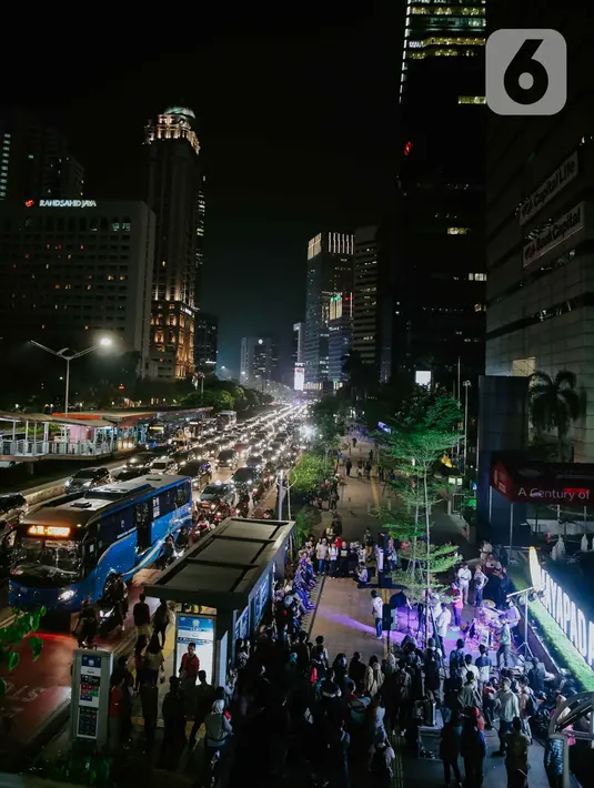 Pejalan kaki menikmati acara bertajuk Musik Tepi Barat dan Timur di jalur pedestrian kawasan Sudirman, Jakarta, Jumat (22/11/2019). Acara musik yang rutin digelar itu bertujuan untuk menghibur para pejalan kaki dan pekerja kantoran yang beraktivitas di kawasan tersebut. (Liputan6.com/Faizal Fanani)