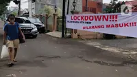 Pejalan kaki melintas di depan spanduk pemberitahuan lockdown di RT 04 / RW 09 Kelurahan Pondok Karya, Tangerang Selatan, Rabu (23/6). Melonjaknya kasus covid-19 di beberapa kawasan membuat sejumlah wilayah melakukan karantina di tingkat RT untuk memutus penyebaran corona (Liputan6.com/Angga Yuniar)