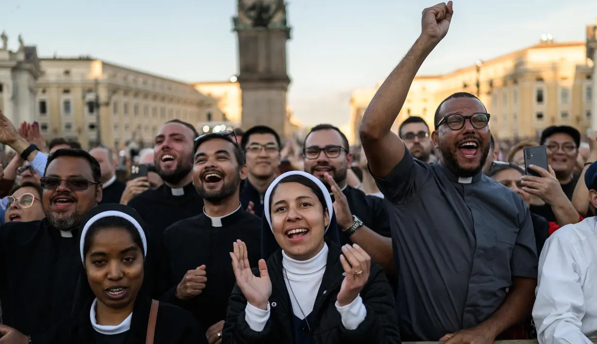 Robert Francis Prevost dikenal sebagai moderat yang dekat dengan Paus Fransiskus dan menghabiskan waktu bertahun-tahun sebagai misionaris di Peru. Tampak dalam foto, para rohaniwan bereaksi smelihat Paus Leo XIV yang baru terpilih, Robert Prevost membuat penampilan pertamanya di balkon loggia utama Basilika Santo Petrus untuk pertama kalinya, setelah para kardinal mengakhiri konklaf, di Vatikan, pada tanggal 8 Mei 2025. (JEFF PACHOUD/AFP)