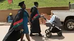 Pasangan wisudawan membawa anak mereka didalam kereta bayi untuk mengikuti upacara wisuda ke-68 di Universitas Makerere di Kampala, Uganda (19/1). (AFP Photo/Michele Sibiloni)